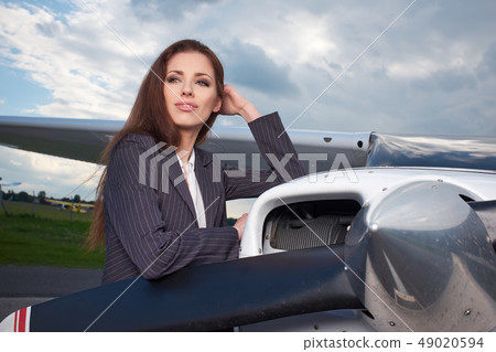 Businesswoman standing by his private plane Businesswoman standing by his private plane 49020594