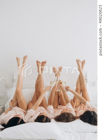 bachelorette party bed lying legs champagne 49020625