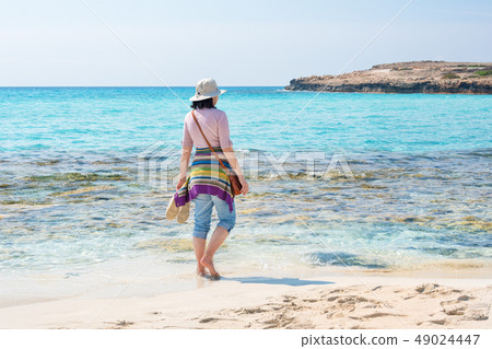 Barefoot woman in hat on the beach. Summer holidays, vacation, travel and people concept Barefoot woman in hat on the beach. Summer holidays, vacation, travel and people concept 49024447