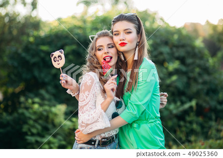 Two pretty and fashionable girlfriends holding 49025360