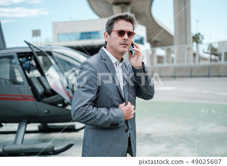 Businessman standing near private helicopter Businessman standing near private helicopter 49025607
