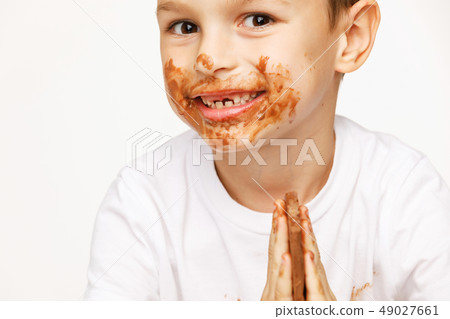 little boy with face and hands in chocolate  49027661