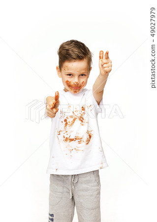 little boy with face and hands in chocolate little boy with face and hands in chocolate 49027979