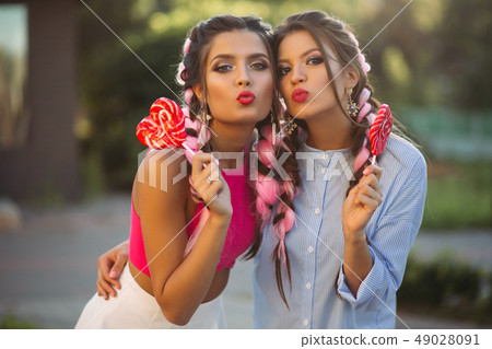 Two girls posing and making duckface with candies Two girls posing and making duckface with candies 49028091