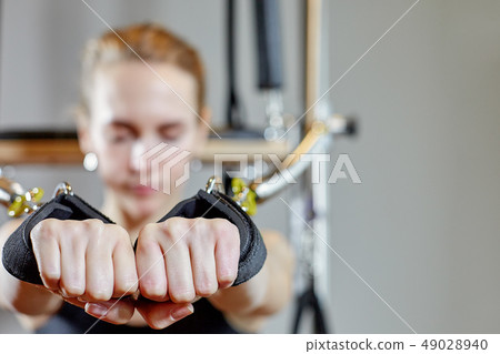 gym woman pilates stretching sport in reformer bed instructor girl. Selective focus on hands 49028940