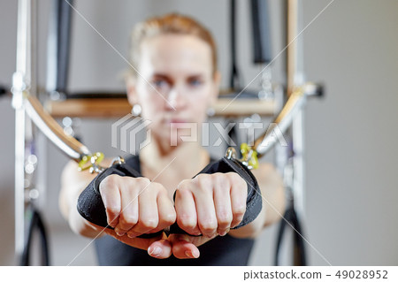 gym woman pilates stretching sport in reformer bed instructor girl. Selective focus on hands 49028952