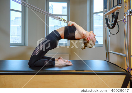 gym woman pilates stretching sport in reformer bed instructor girl. Healthy Smiling Woman Wearing gym woman pilates stretching sport in reformer bed instructor girl. Healthy Smiling Woman Wearing 49029047