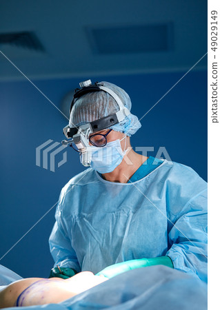 Close up portrait of female surgeon doctor wearing protective mask and hat during the operation 49029149
