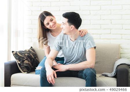 Cute couple in love hugging on the sofa indoors at home, wearing casual outfits Cute couple in love hugging on the sofa indoors at home, wearing casual outfits 49029466