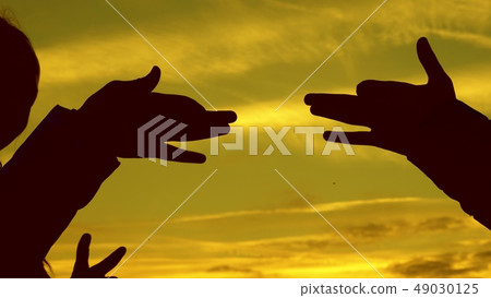 Children make shape of dog shape with hands at sunset. girls hold the gesture of a dog symbol with 49030125