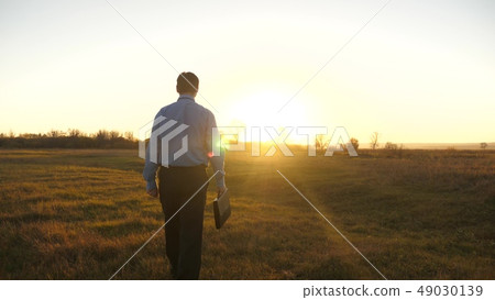 Business man with briefcase goes on beautiful sunset after working day 49030139