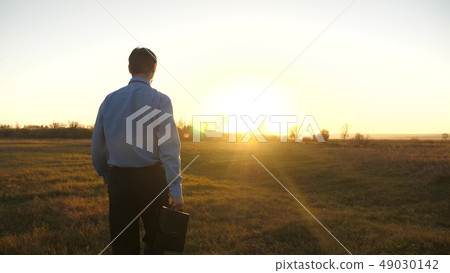 Business man with briefcase goes on beautiful sunset after working day 49030142