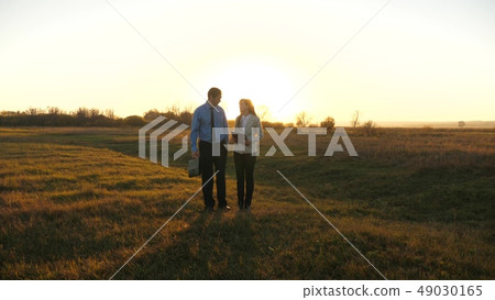 Business man with briefcase and business woman with tablet agree to work together at sunset and Business man with briefcase and business woman with tablet agree to work together at sunset and 49030165