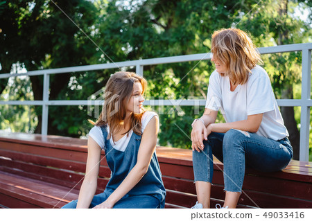 Two beautiful young woman resting on a bench 49033416