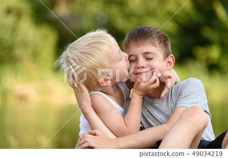 Two little brothers are sitting outdoors. One 49034219