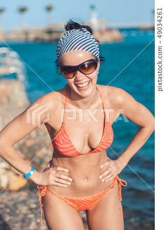 perfectly built Beautiful and young girl with wide hips in a striped orange swimsuit and sunglasses perfectly built Beautiful and young girl with wide hips in a striped orange swimsuit and sunglasses 49034261
