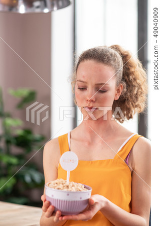 Distressed young woman wearing yellow apron and looking on bowl Distressed young woman wearing yellow apron and looking on bowl 49040909