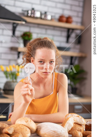 Miserable young woman with light eyes leaning on wooden table Miserable young woman with light eyes leaning on wooden table 49041025
