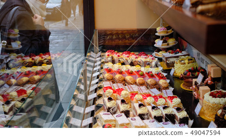 Woman looking at the delicious cake in the show window Woman looking at the delicious cake in the show window 49047594