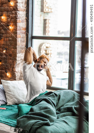 Pleasant good looking man yawning in his bed 49049491