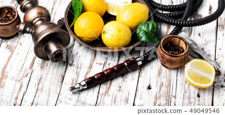 Smoking hookah with lemon flavor Smoking hookah with lemon flavor 49049546