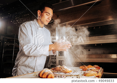 Baker clapping his hands and spilling sugar powder on pastry Baker clapping his hands and spilling sugar powder on pastry 49049833