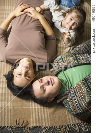 Happy smiling young family lying on the floor Happy smiling young family lying on the floor 49049895