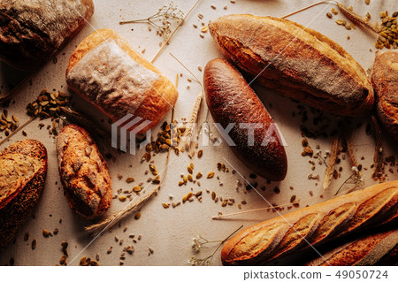 Top view of wheat and rye bread lying on table near seeds Top view of wheat and rye bread lying on table near seeds 49050724