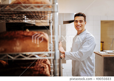 Dark-eyed baker smiling after baking nice yummy bread Dark-eyed baker smiling after baking nice yummy bread 49050883