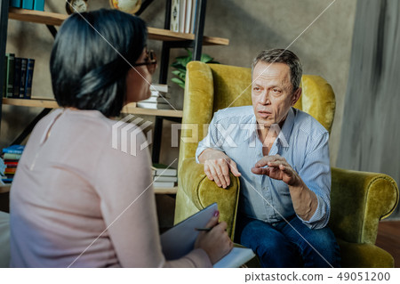 Communicative old man in light shirt talking to specialist 49051200