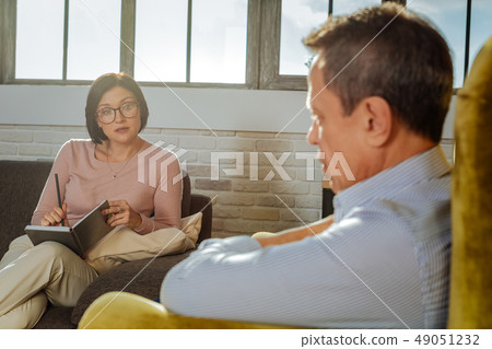 Attentive dark-haired woman in clear glasses asking questions Attentive dark-haired woman in clear glasses asking questions 49051232