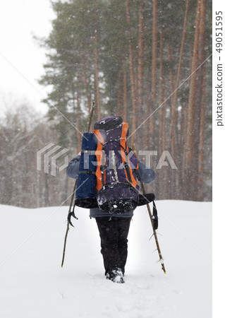 Hiker with backpack and walking sticks in snowy 49051595