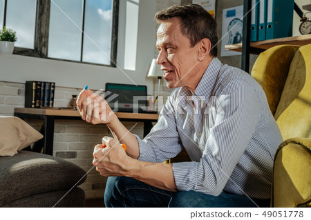 Smiling short-haired man resting in yellow chair and carrying pills 49051778