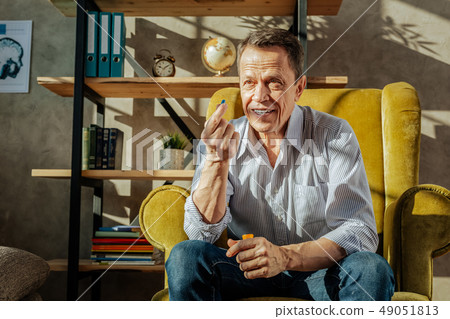 Smiling short-haired man in blue jeans holding a pill Smiling short-haired man in blue jeans holding a pill 49051813