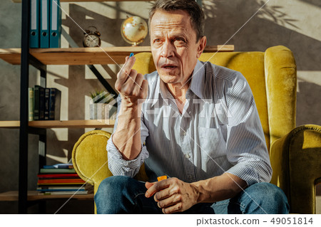 Unpleasant short-haired old man taking pills from the container Unpleasant short-haired old man taking pills from the container 49051814