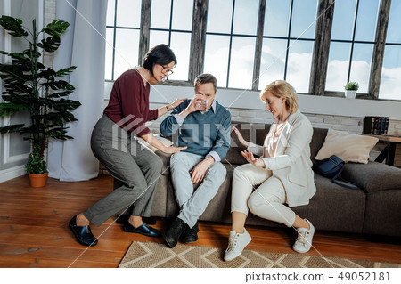 Affected shocked man drinking water while women calming him 49052181