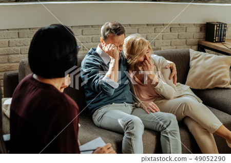 Depressed hugging middle-age couple sitting on a couch and crying 49052290