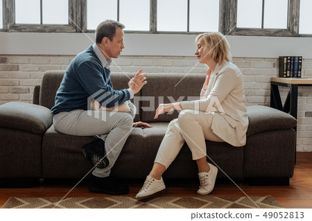 Adult sad couple sitting on couch in front of each other Adult sad couple sitting on couch in front of each other 49052813