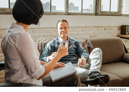 Smiling good-looking man having pleasant conversation with dark-haired doctor Smiling good-looking man having pleasant conversation with dark-haired doctor 49052969