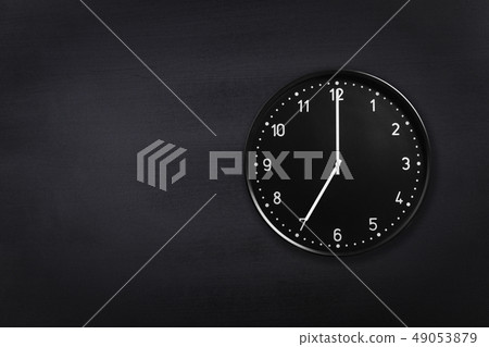 Wall clock showing seven o'clock on black chalkboard background. Office clock showing 7am or 7pm on Wall clock showing seven o'clock on black chalkboard background. Office clock showing 7am or 7pm on 49053879