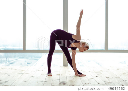 Concentrated short-haired woman doing yoga exercises and raising hands 49054262