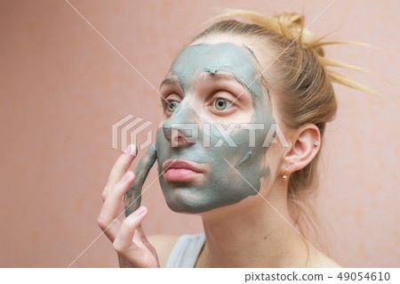 beautiful woman puts a mask of clay on the face  49054610