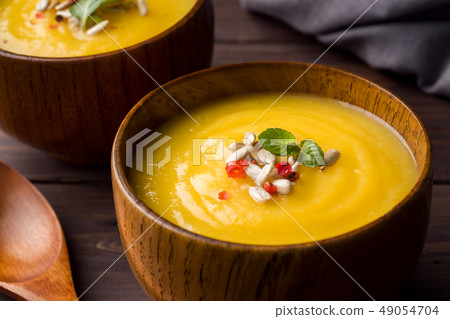 Pumpkin soup mashed with spices in wooden bowls Pumpkin soup mashed with spices in wooden bowls 49054704