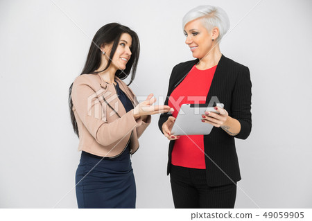 Portrait of two young buisness ladies in costumes isolated on background Portrait of two young buisness ladies in costumes isolated on background 49059905