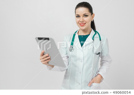 Portrait of brunet in doctors costume with a modern tablet in her hands isolated on background Portrait of brunet in doctors costume with a modern tablet in her hands isolated on background 49060054