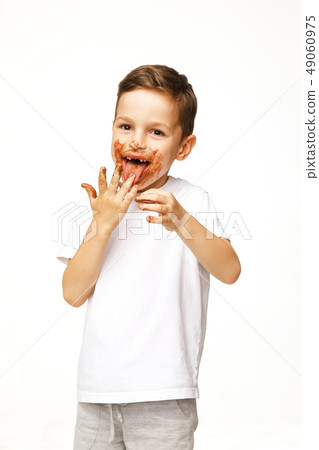 little boy with face and hands in chocolate little boy with face and hands in chocolate 49060975