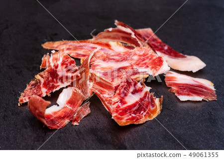 Delicious sliced Spanish Ham, Jamon iberico on black slate. Delicious sliced Spanish Ham, Jamon iberico on black slate. 49061355