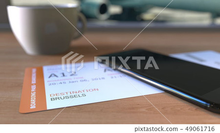 Boarding pass to Brussels and smartphone on the table in airport while travelling to Belgium. 3D 49061716