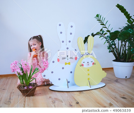 Easter 2019 Beautiful little girl in a dress with Easter decorations. Big Easter bunnies. A lot of Easter 2019 Beautiful little girl in a dress with Easter decorations. Big Easter bunnies. A lot of 49063839