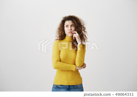 Portrait of young tricky woman touching lock of hair meaning she has something in mind with facial Portrait of young tricky woman touching lock of hair meaning she has something in mind with facial 49064331